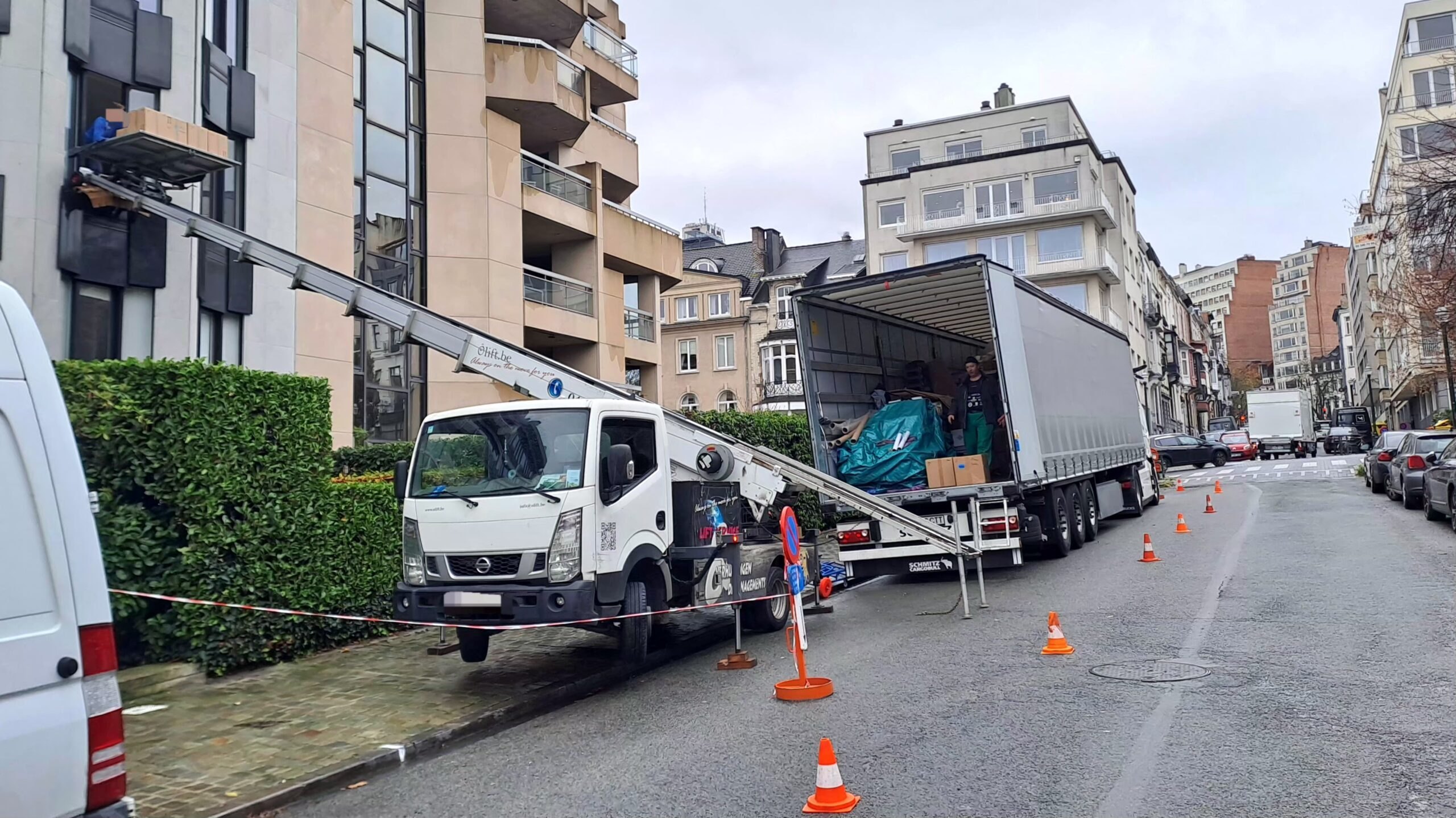 Lift de déménagement vers un immeuble à balcons, semi-remorque chargée de mobilier emballé, dans le centre de Bruxelles